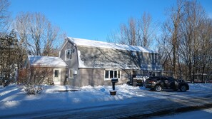 A two-story house with a snow-covered roof and a driveway leading to a parked SUV. - Spacious house in quiet village across from The Lost Kitchen (Freedom)