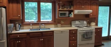A kitchen with wooden cabinets, a microwave, a stove, and a dishwasher.
