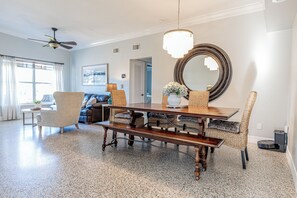 A dining area with a wooden table, chairs, and a bench. There is a ceiling fan, a large mirror, and a window with curtains. - Central getaway for exploring Bradenton and Sarasota with ease (Bradenton)