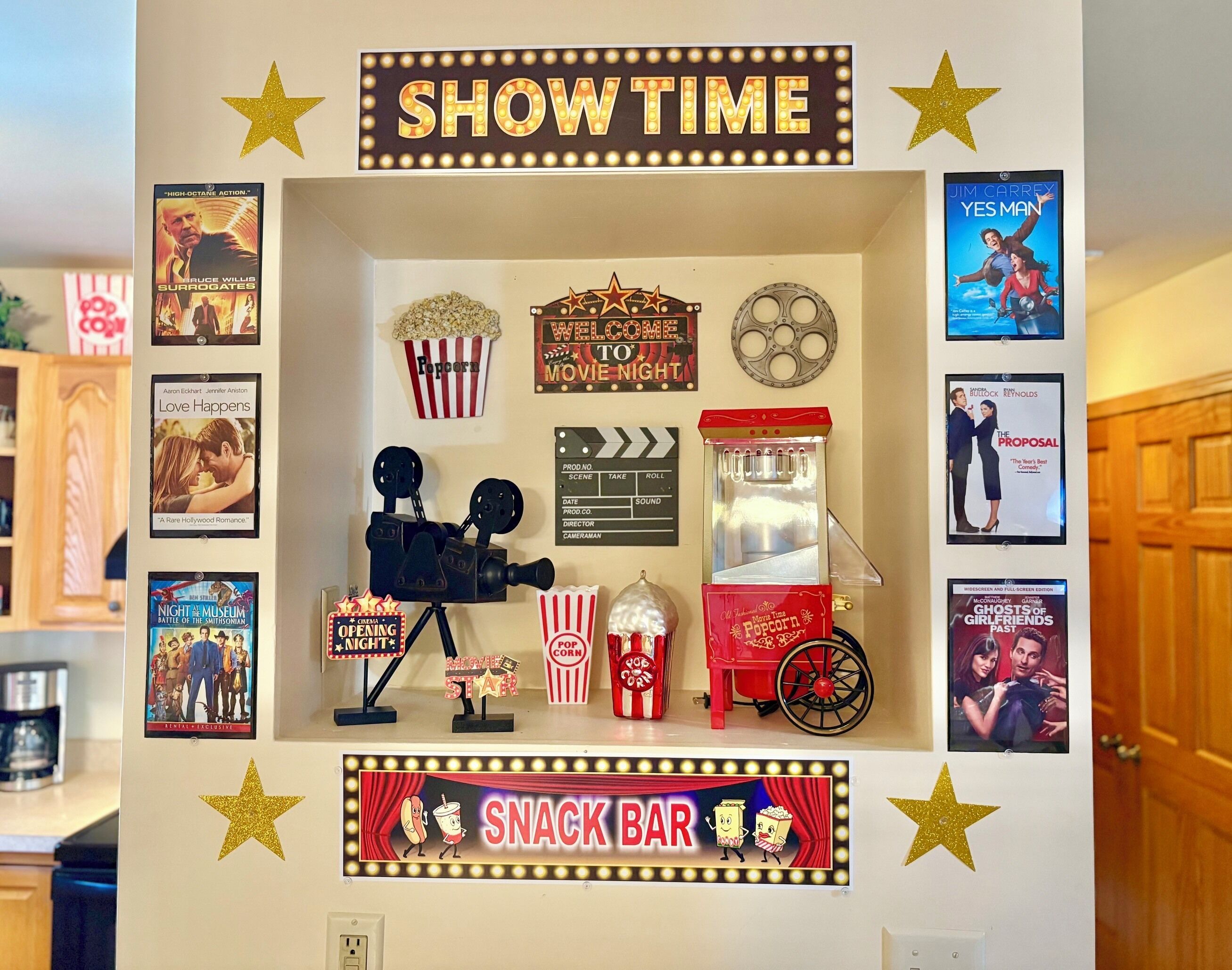 A wall decorated with movie posters, a popcorn stand, and a clapperboard, indicating a themed movie night setup.