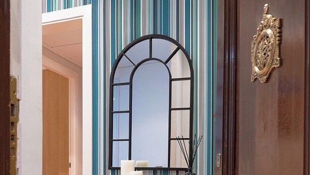A wooden door with a brass handle and a decorative plate, a mirrored wardrobe with multiple drawers, and a striped wall in the background. - Designer Apart •High Floor Fast WiFi, Sagrada (Barcelona)