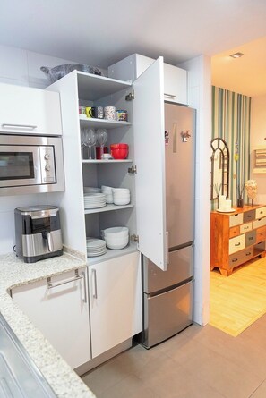 Eine kompakte Küche mit Einbauofen, Kaffeemaschine und Kühlschrank mit Gefrierfach.
