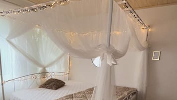 Ein Bett mit Baldachin, ein Nachttisch und ein an der Wand befestigter Bilderrahmen.
