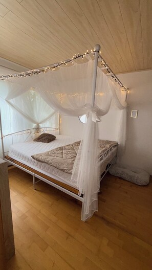A bed with a canopy, a bedside table, and a wall-mounted picture frame.
