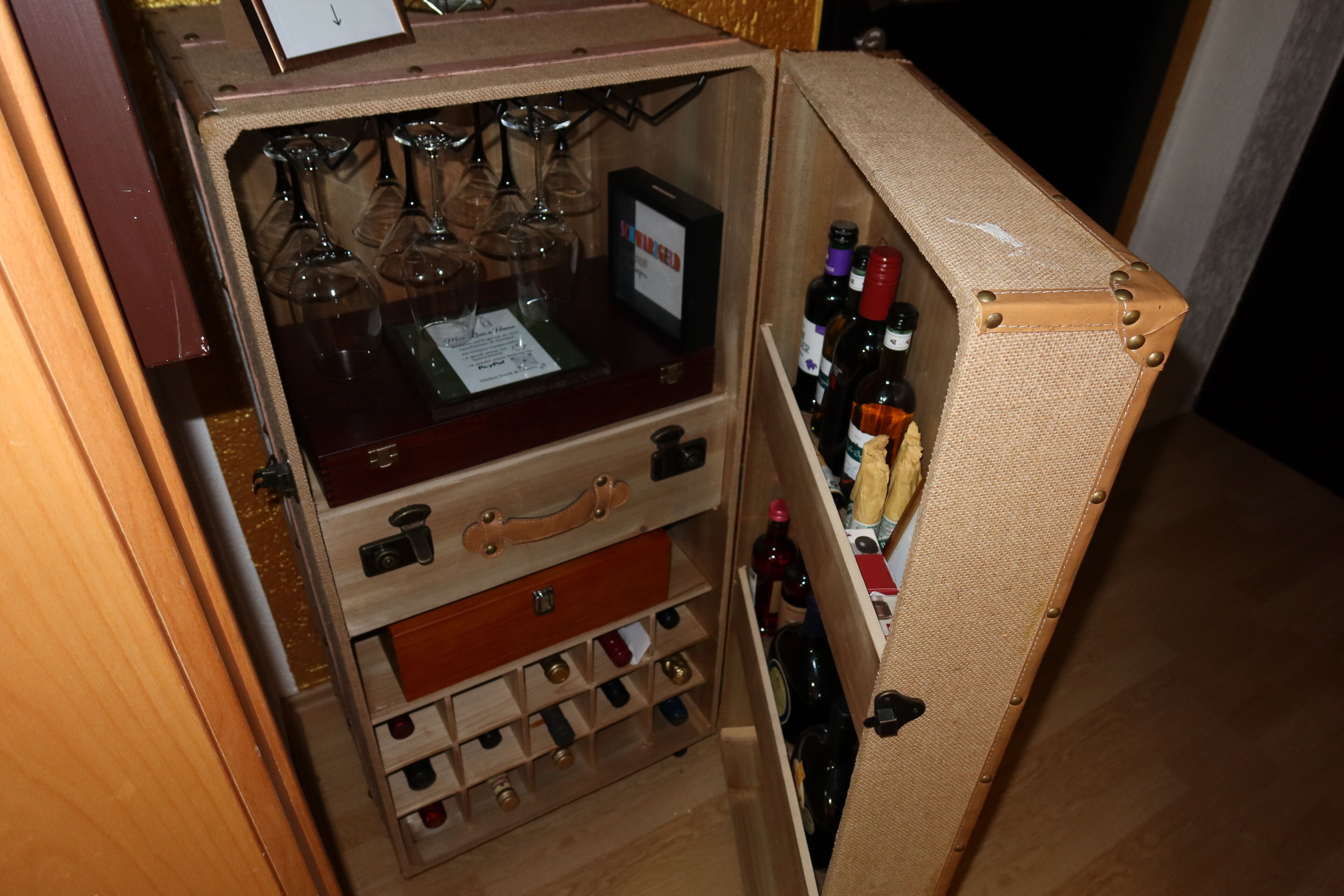 A compact wine storage unit with multiple compartments for wine bottles and glasses.