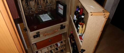 A compact wine storage unit with multiple compartments for wine bottles and glasses.