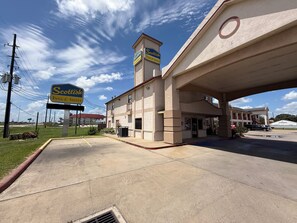 A motel with a signboard, a parking lot, and a building with a balcony.