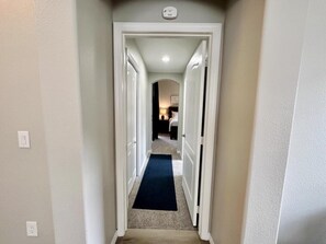 A narrow hallway with white walls and a dark carpet leading to a bedroom. - Tuscan Hills 5BR Villa | Private Pool & Spa (Davenport)