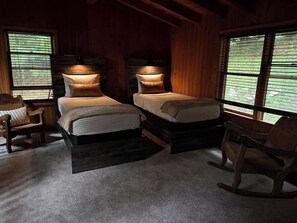 A cabin-style bedroom with two beds, wooden headboards, and large windows. - Wolf Laurel Cabin with Hot Tub Near Skiing (Mars Hill)