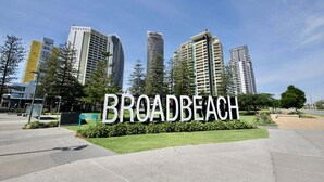 Un cartel indica BROADBEACH, con modernos edificios de gran altura al fondo.