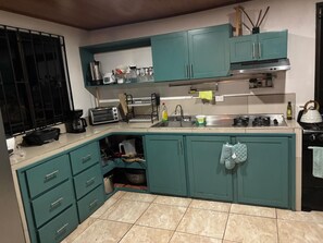 A compact kitchen with teal cabinets, a built-in oven, a sink, and a stove. - Sonado Vacation Home for Large Groups (La Perla)