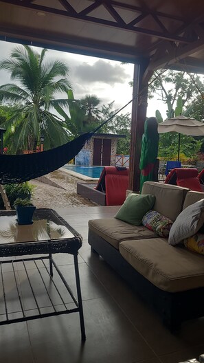 A covered outdoor seating area with a sofa, a table, and a hammock. - Sonado Vacation Home for Large Groups (La Perla)