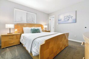 A bedroom with a bed, bedside tables, a nightstand, a lamp, a window with blinds, and a wall-mounted painting. - ᨒStylish 4BR | Movie Lounge | 10 min to Ft Carsonᨒ (Colorado Springs)