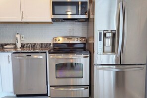 Una cocina con electrodomésticos de acero inoxidable, incluyendo un microondas, horno y refrigerador.