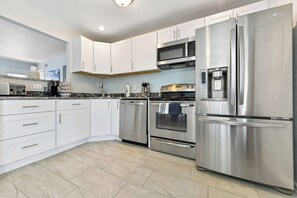 A modern kitchen with white cabinets, stainless steel appliances, and a tiled backsplash.