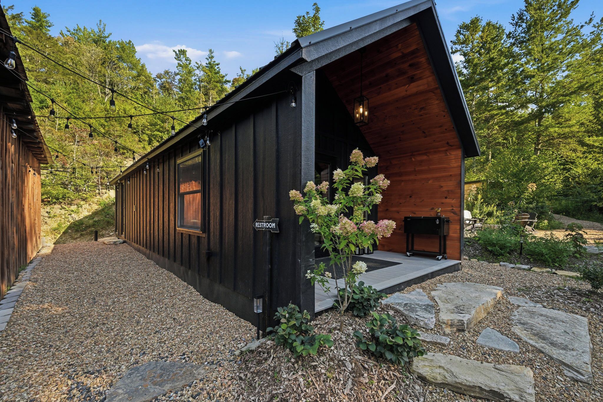 A cabin with a wooden exterior, a visible restroom sign, and a gravel driveway.