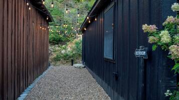 A narrow pathway flanked by wooden buildings with a sign indicating a restroom.
