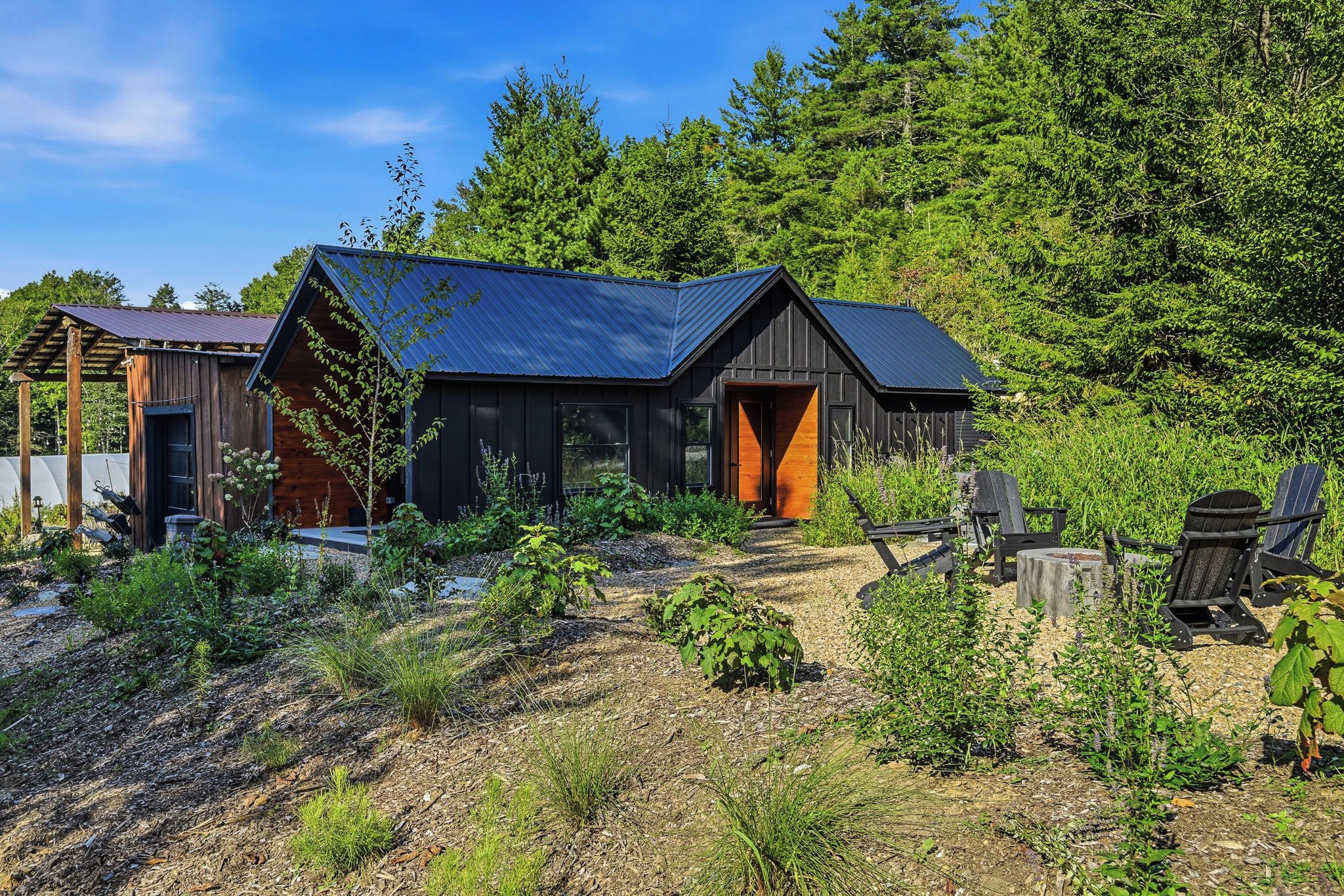A cabin with a dark exterior, a sloped roof, and a wooden door.
