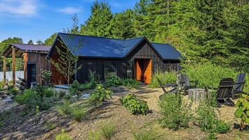 A cabin with a dark exterior, a sloped roof, and a wooden door.