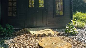 A wooden cabin with a gravel driveway, surrounded by trees.
