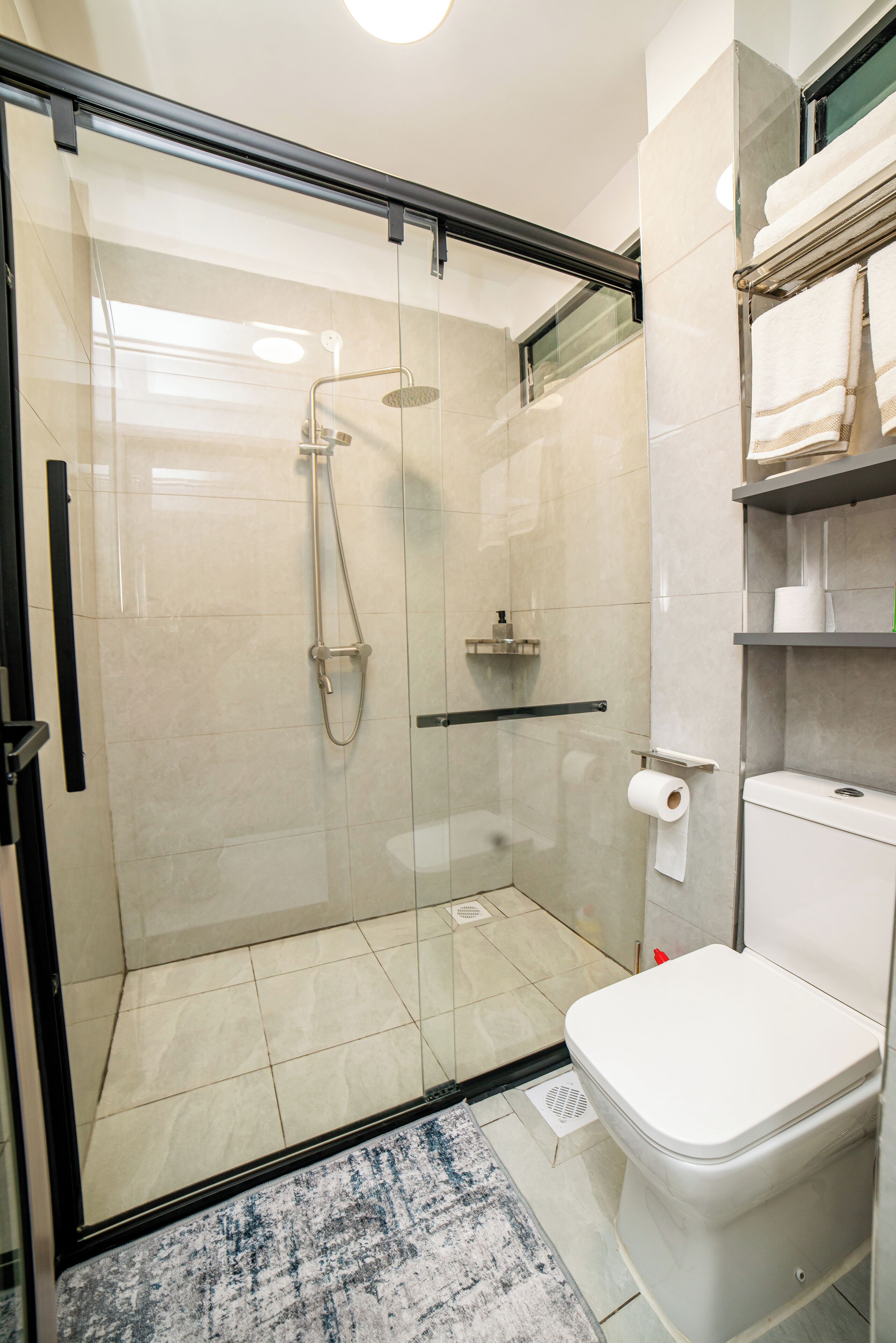 Ein modernes Badezimmer mit einer Duschkabine, einer Toilette und einem Handtuchhalter.