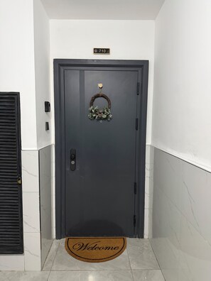 Una puerta oscura con felpudo y una placa con un número.
