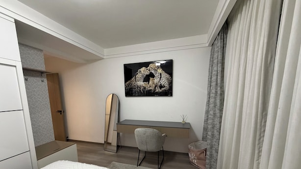 Une chambre à coucher avec un lit, un bureau, une chaise, un miroir et un tableau accroché au mur.