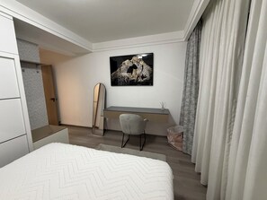 Une chambre à coucher avec un lit, un bureau, une chaise, un miroir et un tableau accroché au mur.