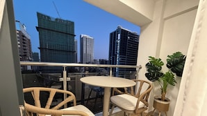 Un balcon avec des fauteuils en osier, une petite table ronde et une plante en pot.