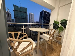 A balcony with wicker chairs, a small round table, and a potted plant. - Charming 2BR apartment in beautiful Nairobi I Private Balcony & City Views (Nairobi)