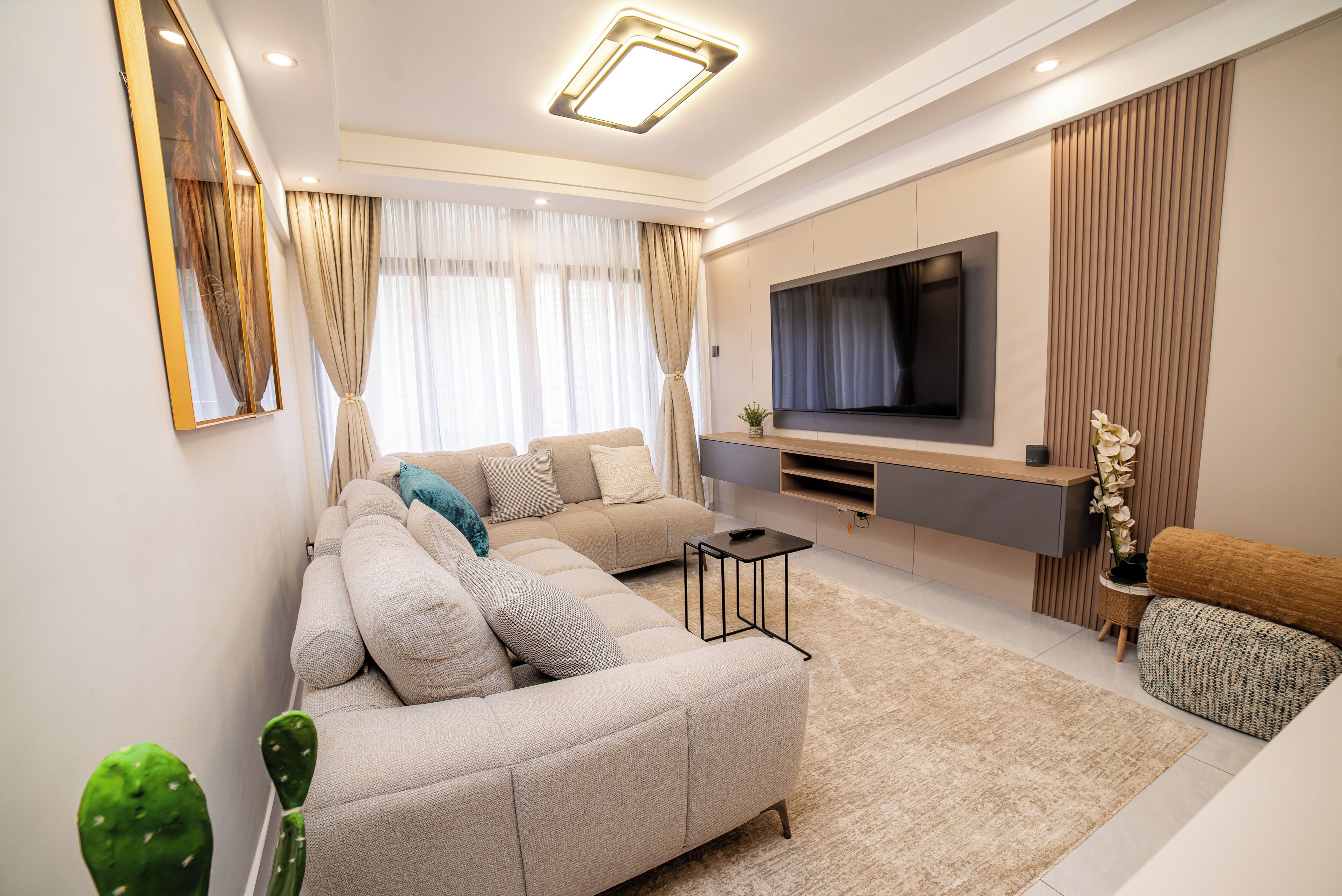 A modern living room with a sectional sofa, a flat-screen TV, and a minimalist design.