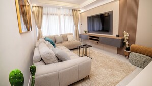 Un salon moderne avec un canapé d’angle, un téléviseur à écran plat et un design minimaliste.