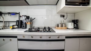 Une cuisine moderne équipée d’une cuisinière à gaz, d’une machine à café et de divers ustensiles.