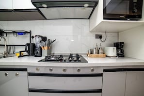 A modern kitchen with a gas stove, coffee maker, and various utensils. - Charming 2BR apartment in beautiful Nairobi I Private Balcony & City Views (Nairobi)