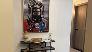 Un couloir orné d’un tableau encadré, une petite table sur laquelle sont disposés des objets décoratifs, et une paire de chaussures.