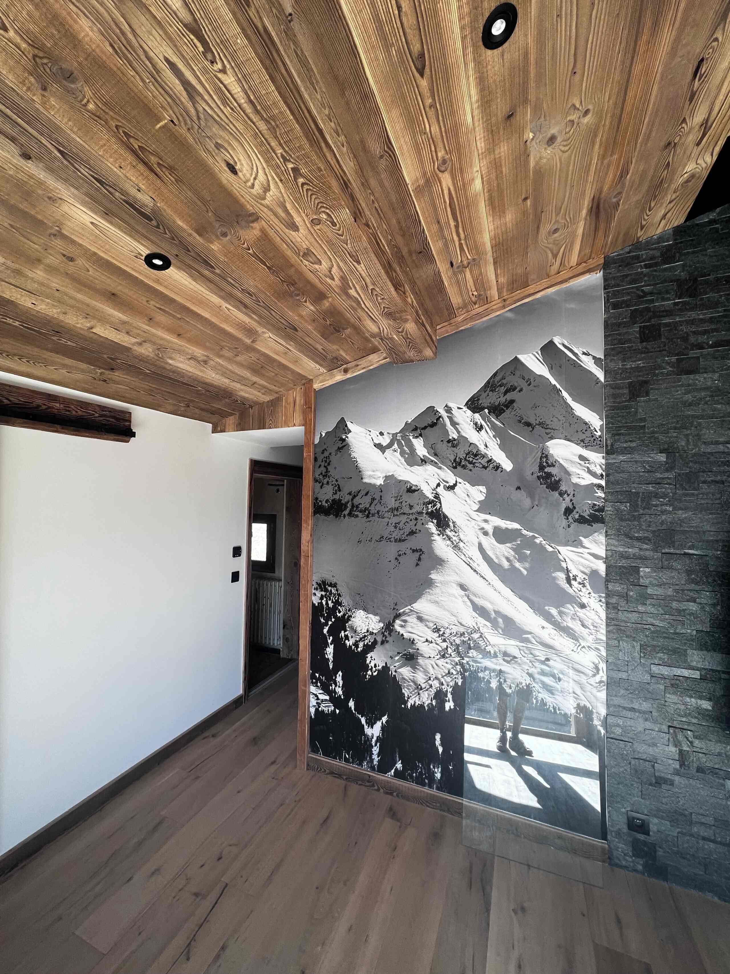 Een gang met houten plafond en een groot muurschildering van een berglandschap.