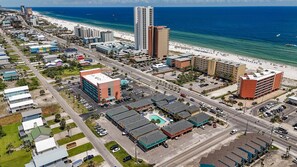 Une vue aérienne d’une ville côtière, avec une plage, des immeubles de grande hauteur et un parking doté d’une piscine.