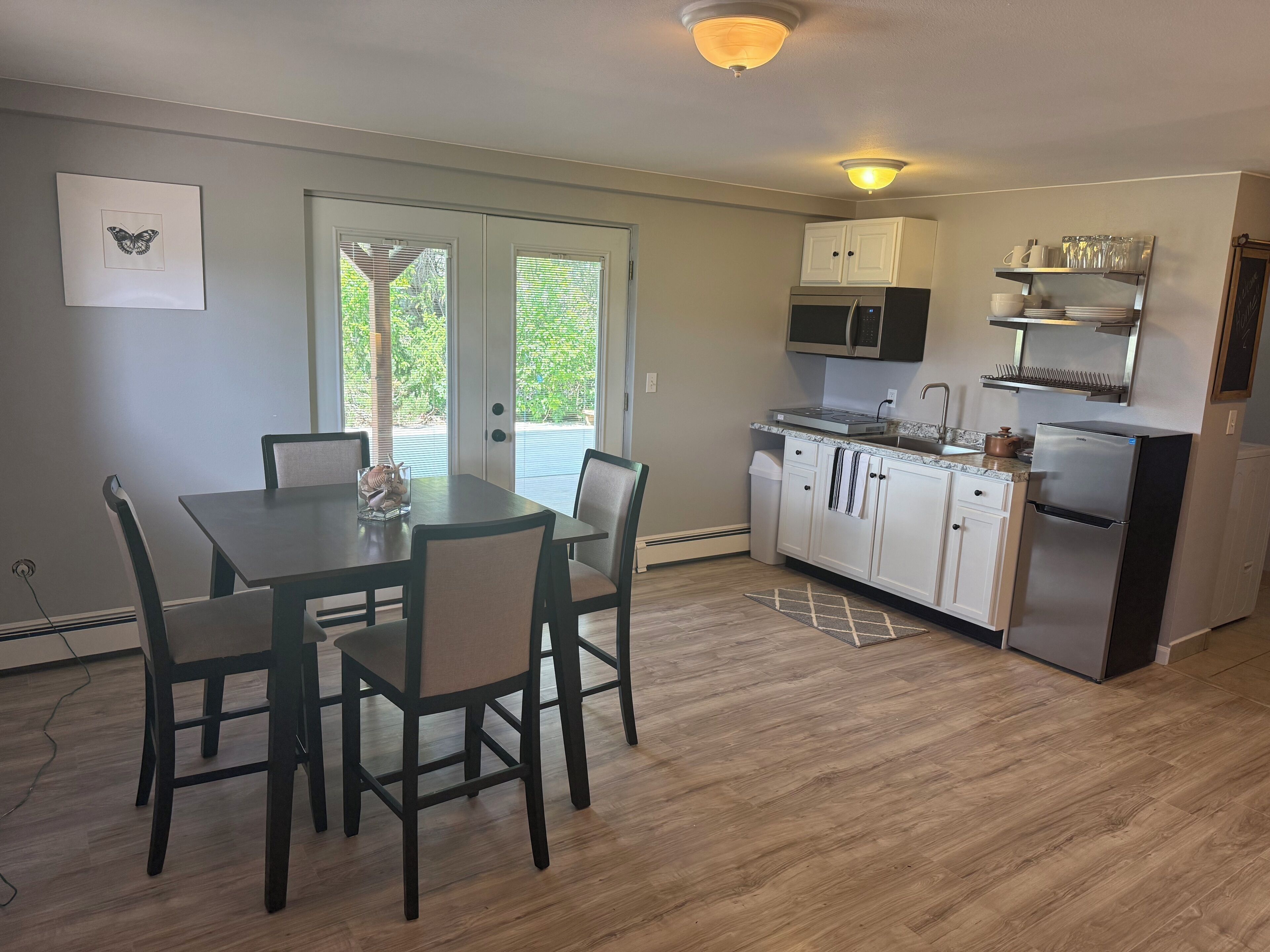A compact kitchen with white cabinets, a stainless steel refrigerator, and a dining area with a table and chairs.