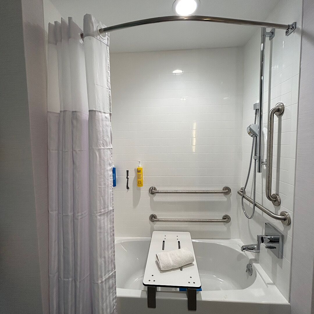 Un baño moderno con ducha a ras de suelo, barras de apoyo y un perchero para toallas.