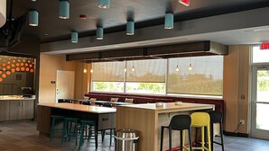 A modern interior with a central island, bar stools, and a trash can. - Tru By Hilton Shippensburg (Shippensburg)