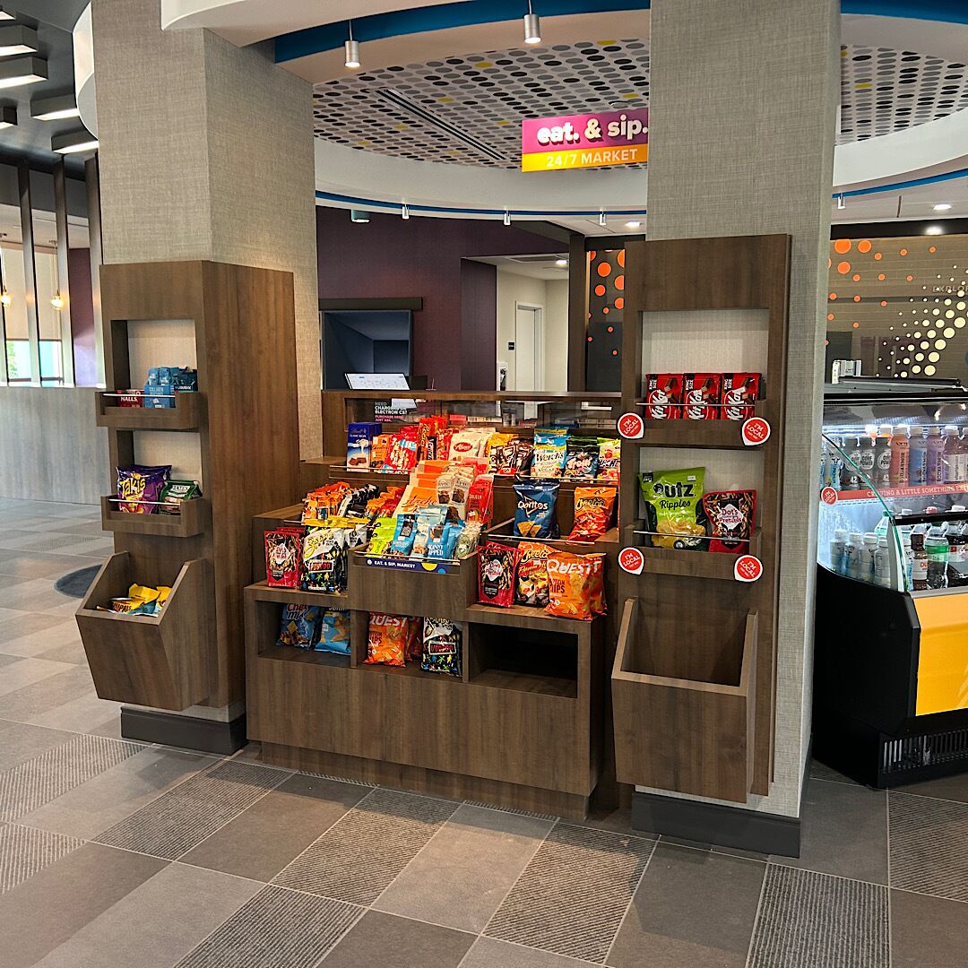 A snack kiosk with a variety of packaged snacks and a 24/7 market sign.