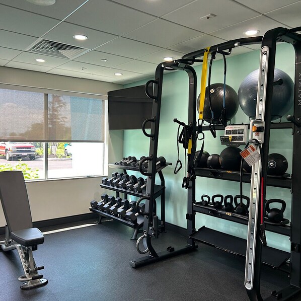 A gym with weightlifting equipment, kettlebells, and dumbbells.