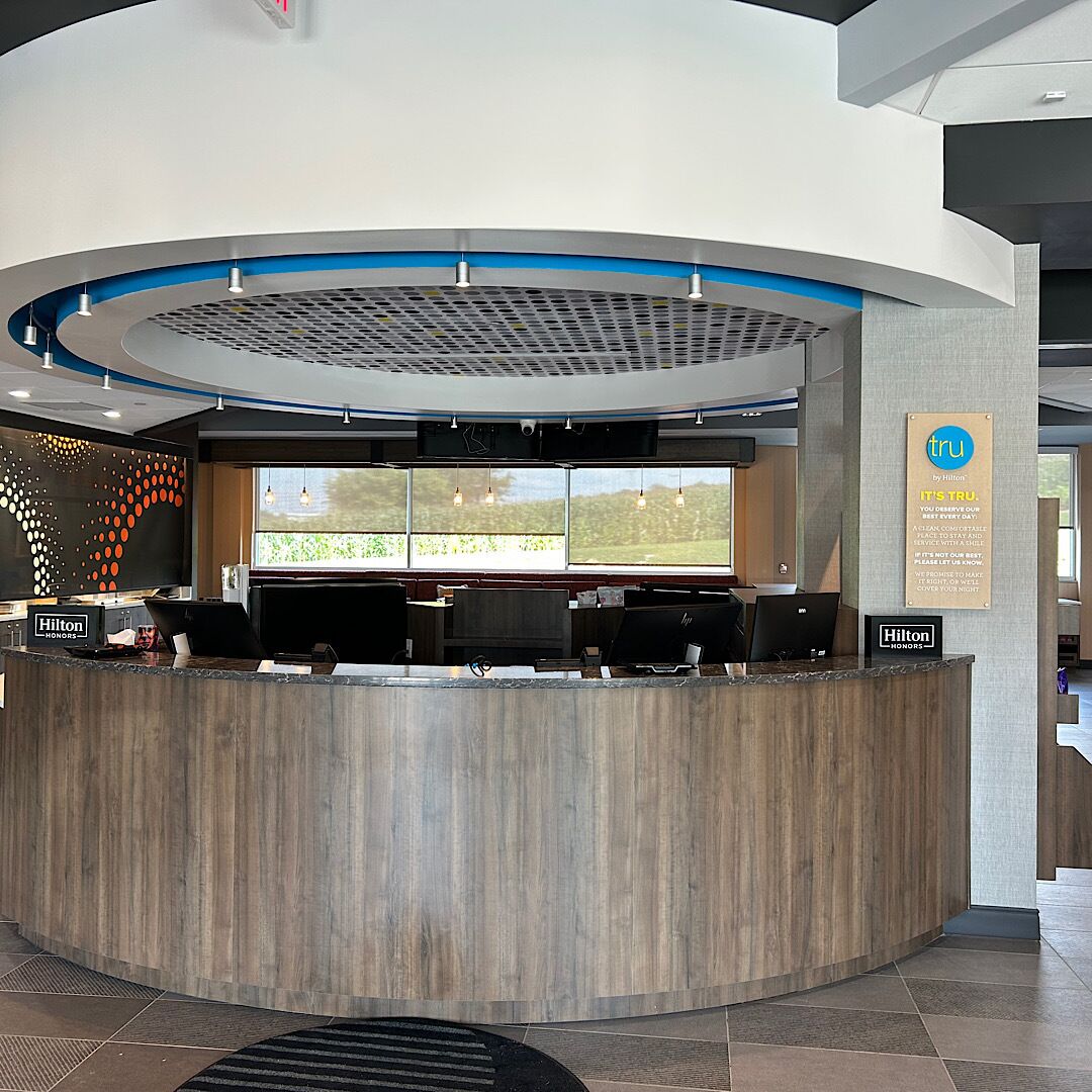 A hotel reception desk with a modern design, large windows, and a view of the outdoors.