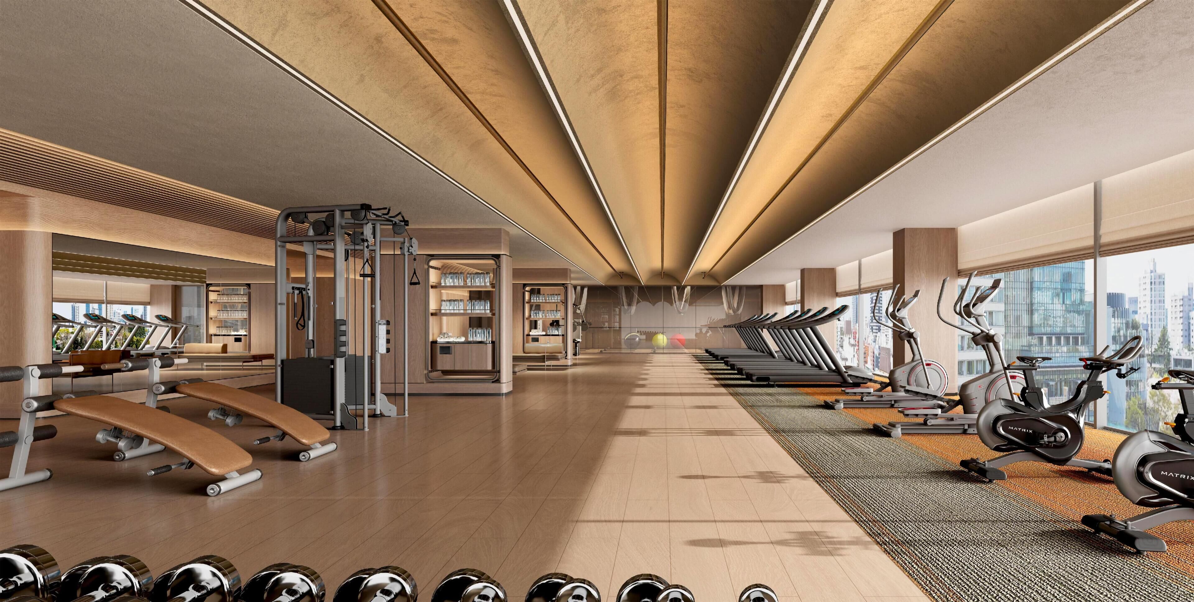Un gimnasio moderno con cintas de correr, elípticas y equipo de pesas.