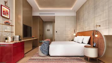 Un dormitorio moderno con una cama grande, un televisor, un aparador rojo y una alfombra estampada.