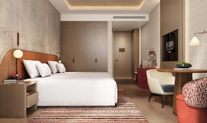 A modern hotel room with a large bed, a desk, a chair, and a television. - Anor And Saffron Tashkent, Curio Collection By Hilton (Tashkent)
