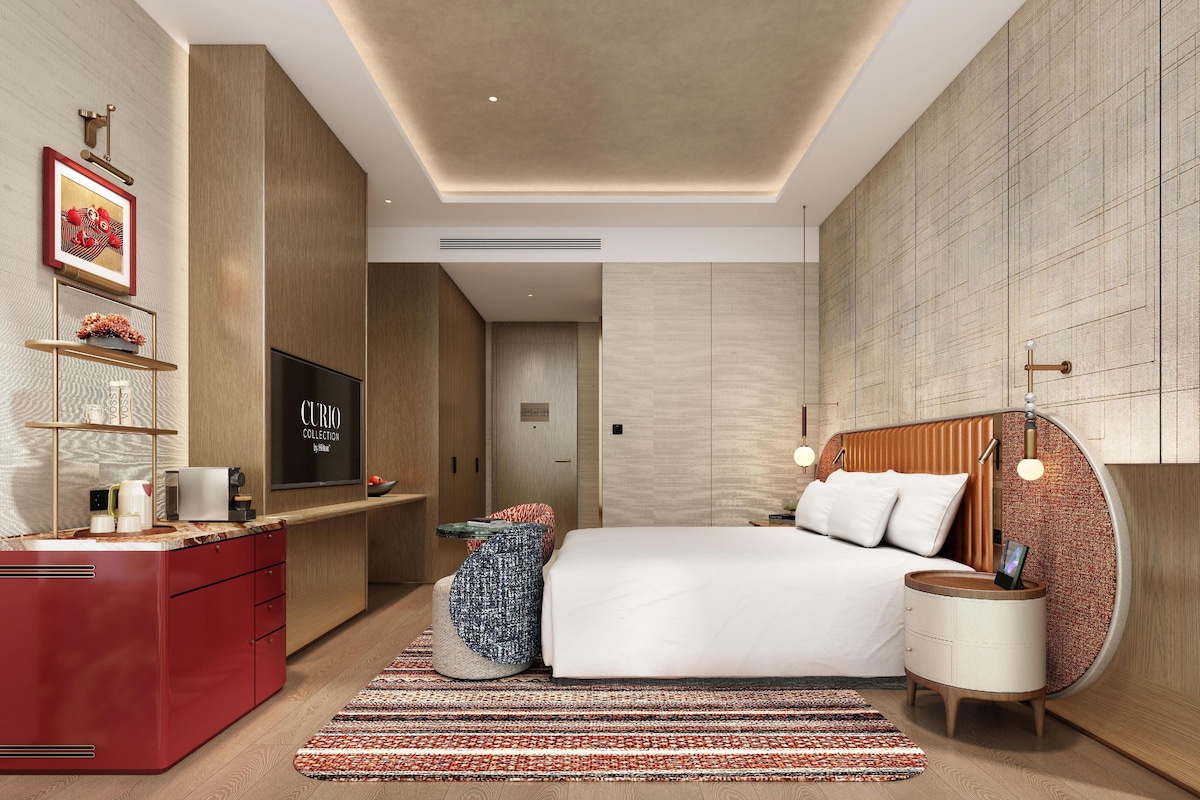A modern bedroom with a bed, bedside table, and a TV mounted on the wall.