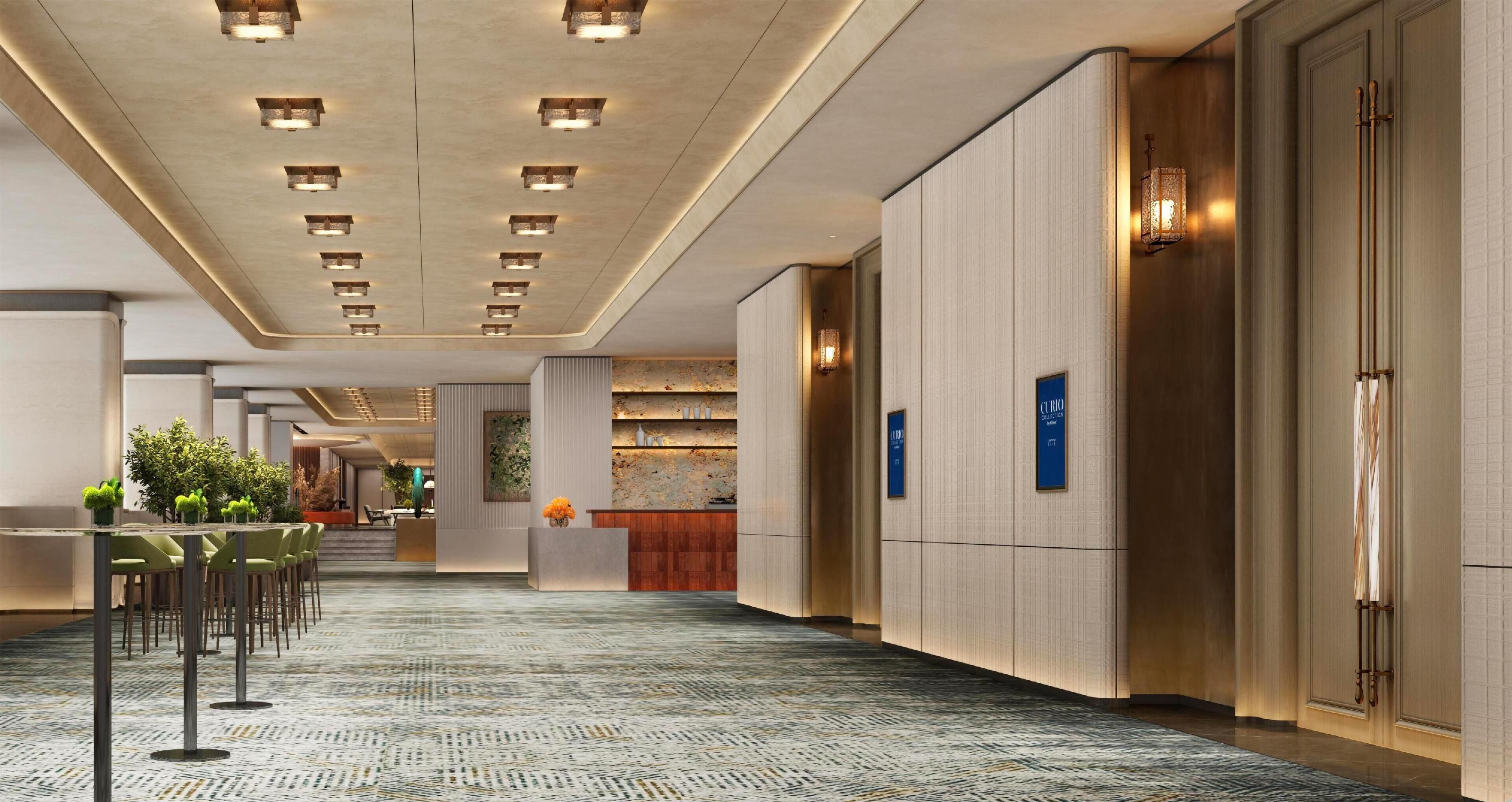 Un hall d’hôtel comprenant un comptoir d’accueil, un espace salon et un tapis à motifs.