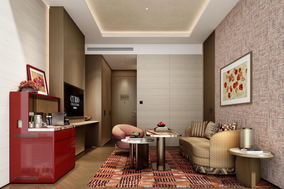 A modern living room with a sofa, a coffee table, a red cabinet, and a television.