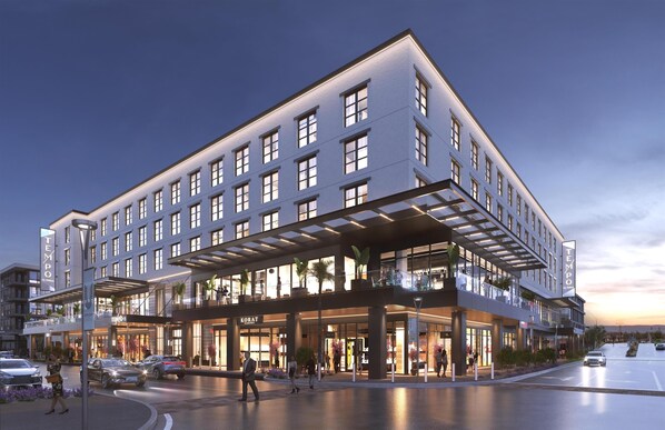 A modern hotel with a prominent entrance, multiple floors, and a covered outdoor area.